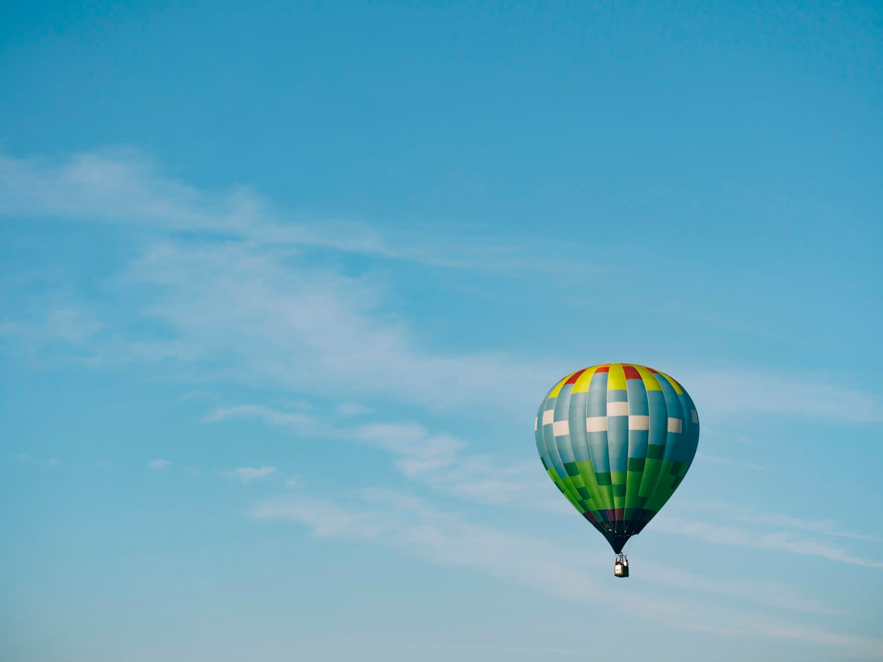 A colorful hot air balloon rising into a blue sky