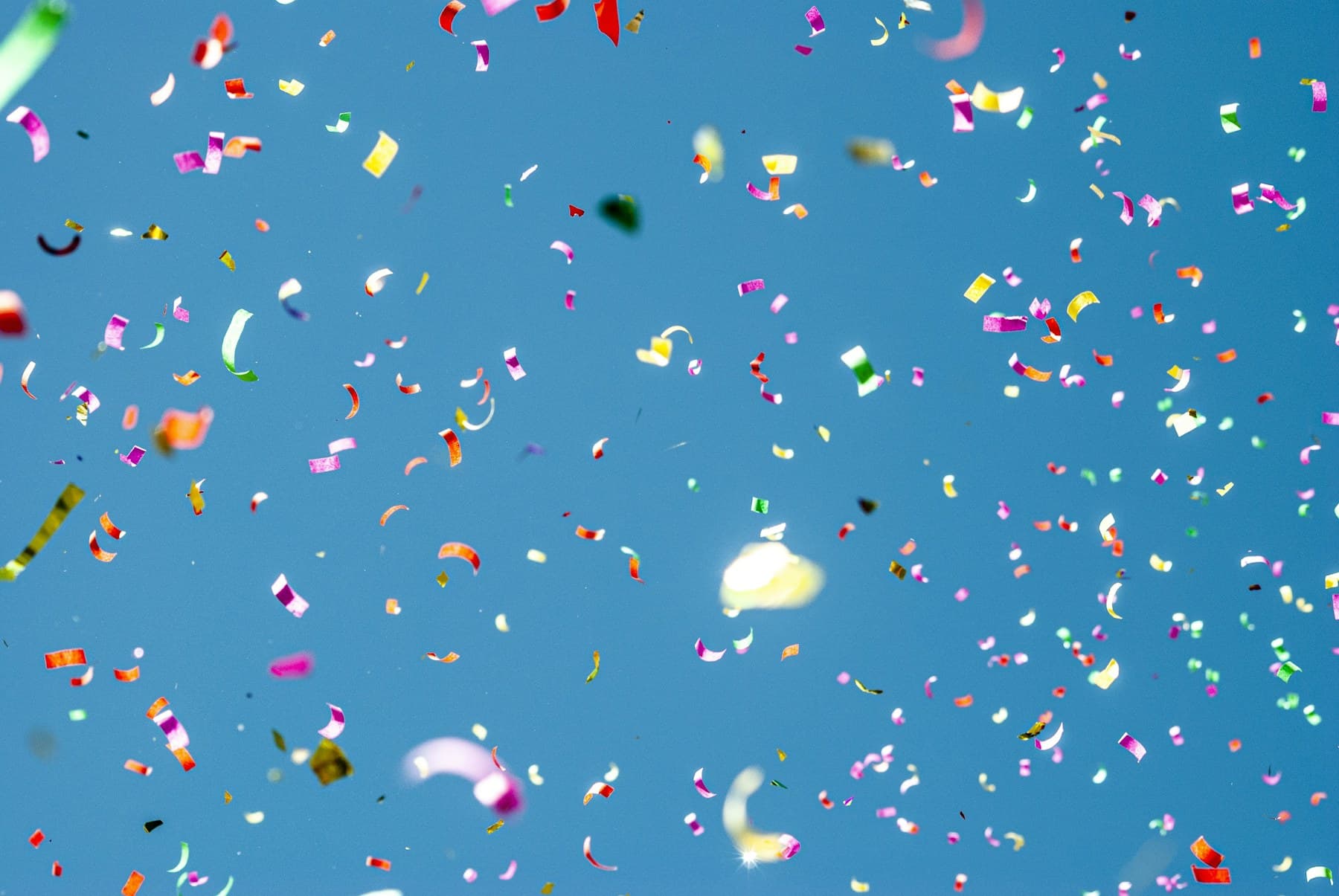 Colorful confetti floating in a blue sky
